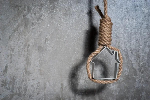 Petite maison encadrée d'une corde de bourreau au-dessus du mur de béton gris — Photo