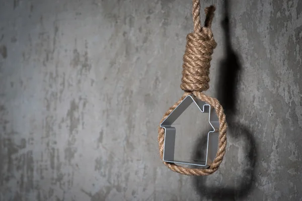 Petite maison encadrée d'une corde de bourreau au-dessus du mur de béton gris — Photo