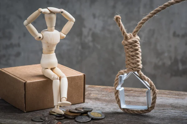 Small wooden dummy sitting with hangman's noose, house and coins — Stock Photo, Image