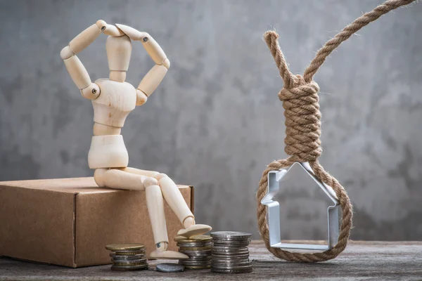 Small wooden dummy sitting with hangman's noose, house and coins — Stock Photo, Image