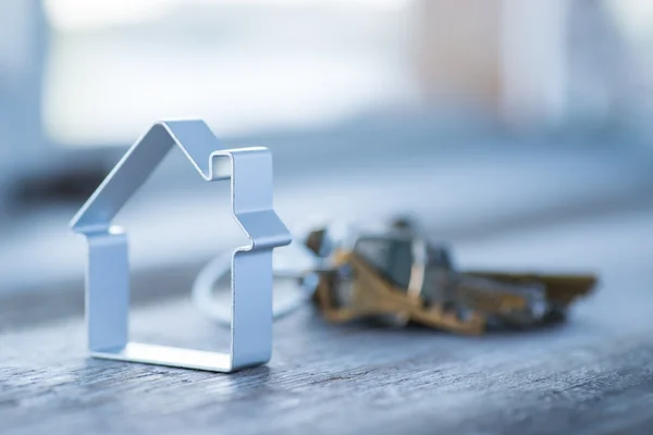 A bunch of old worn keys with metal house on the wooden surface — Stock Photo, Image