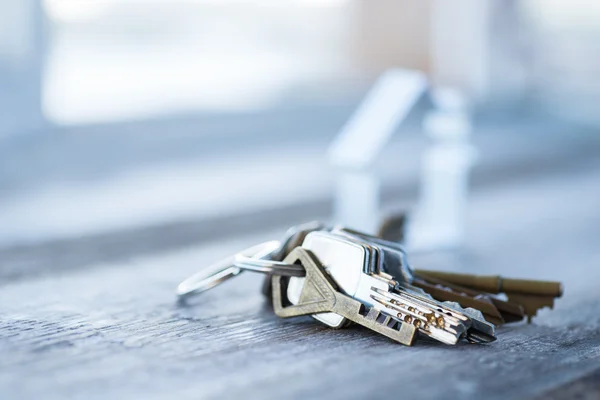 A bunch of old worn keys with metal house on the wooden surface — Stock Photo, Image