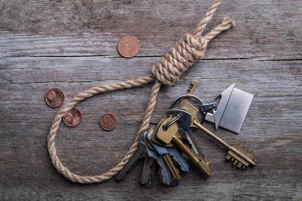Cuerda del ahorcado con casa, llaves y dinero en la superficie de madera marrón —  Fotos de Stock