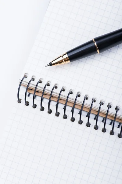 Een spiraal notebook met zwarte balpen over de witte achtergrond, geïsoleerd — Stockfoto