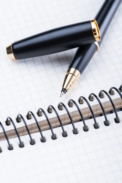 Een spiraal notebook met zwarte balpen over de witte achtergrond, geïsoleerd — Stockfoto