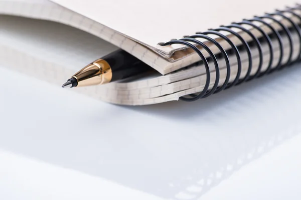 Een spiraal notebook met zwarte balpen over de witte achtergrond, geïsoleerd — Stockfoto