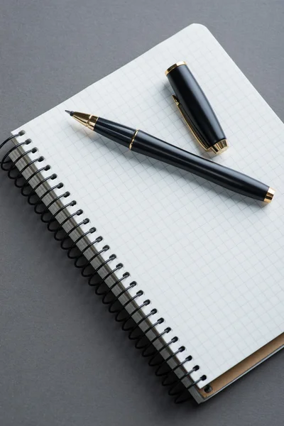 Un carnet spirale avec stylo bille noir sur fond gris — Photo