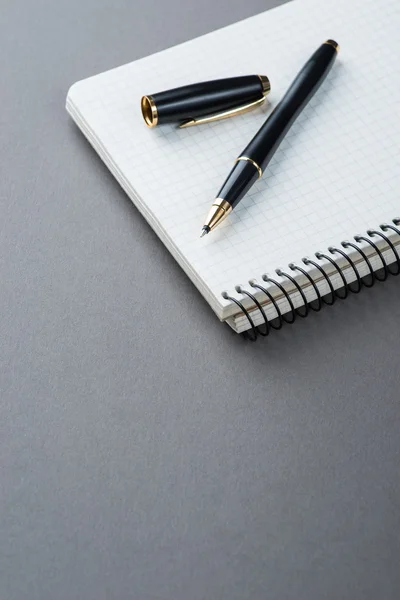 A spiral notebook with black ball pen over the grey background — Stock Photo, Image