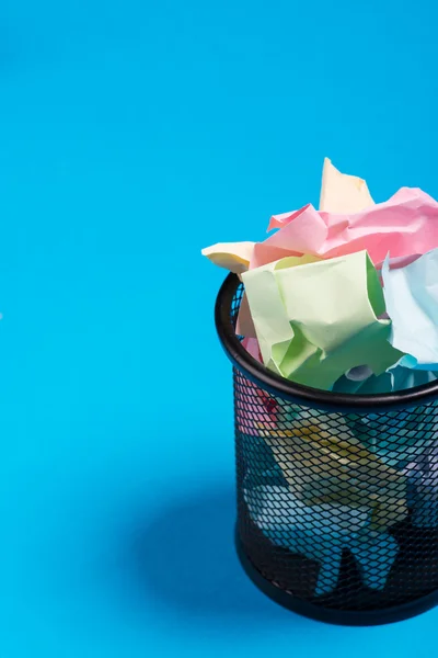 Poubelle de bureau avec papier couleur froissé sur le fond bleu — Photo