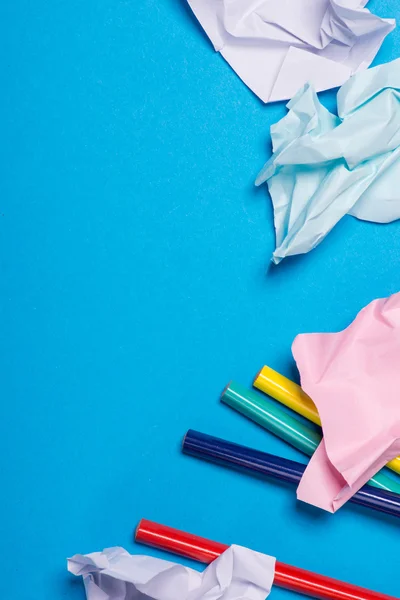 Plusieurs crayons de couleur avec du papier de couleur froissé sur le fond bleu — Photo