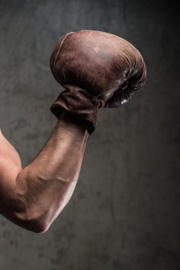 Tough caucasian male's hand in old vintage boxing gloves, ready to fight