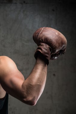 Tough caucasian male's hand in old vintage boxing gloves, ready to fight