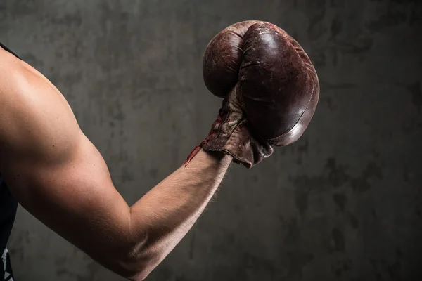 Tough caucasian male's hand in old vintage boxing gloves, ready to fight