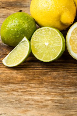 Fresh and juicy lemons and lime on a wooden surface clipart