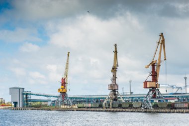 Cargo cranes and railway cars in the port under the stormy sky
