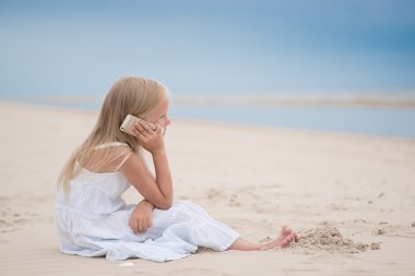 Beautiful young girl talking on the phone at the seaside