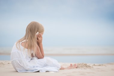 Beautiful young girl talking on the phone at the seaside