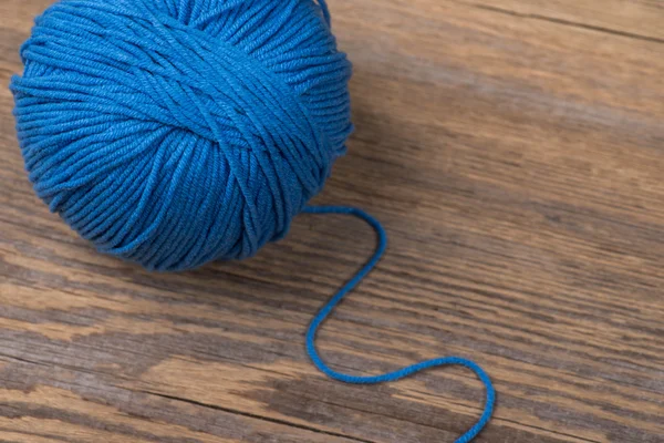 Ball of blue knitting yarn on wooden surface — 图库照片