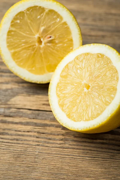 Halves of a fresh and juicy lemon on wooden table — Stock Fotó