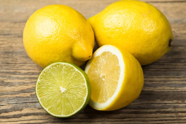 Fresh and juicy lemons and lime on a wooden surface — ストック写真