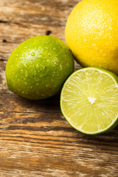 Limones y lima frescos y jugosos sobre una superficie de madera — Foto de Stock