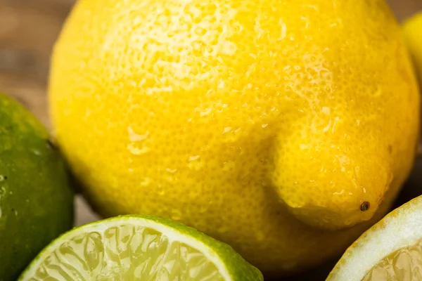 Limoni freschi e succosi e calce su una superficie di legno — Foto Stock