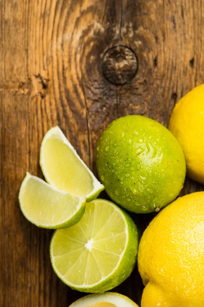 Limones y lima frescos y jugosos sobre una superficie de madera — Foto de Stock