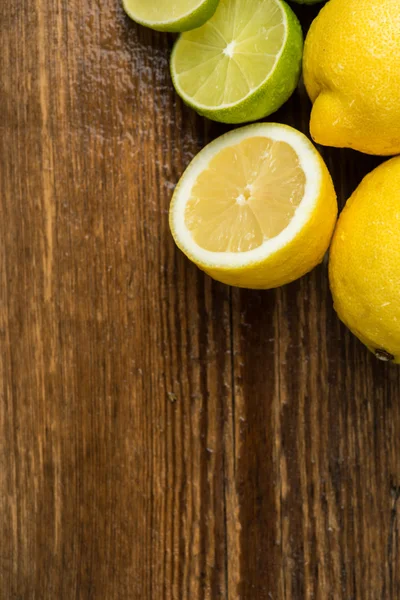 Limoni freschi e succosi e calce su una superficie di legno — Foto Stock