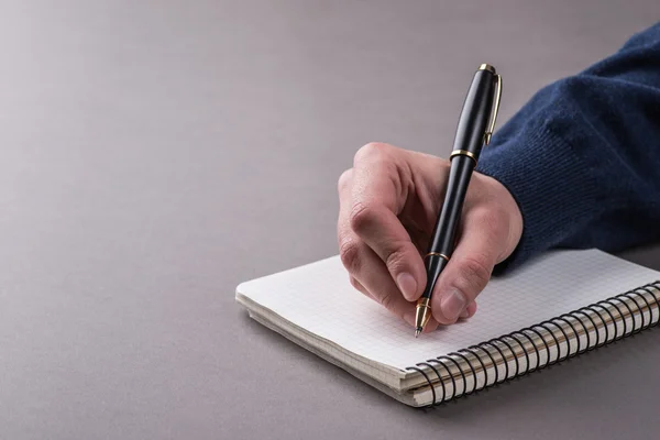 Uomo che scrive una nota con penna a sfera nera in mano — Foto Stock