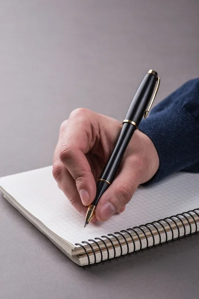 Man writing a note with black ball pen in his hand — Stock fotografie