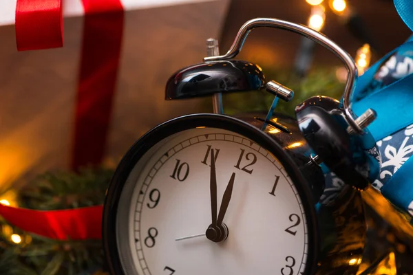 Árbol de Navidad, regalos, luces y reloj sobre la pared de madera — Foto de Stock