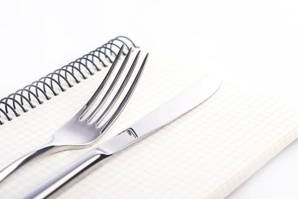Fourchette, couteau et bloc-notes sur le fond blanc — Photo