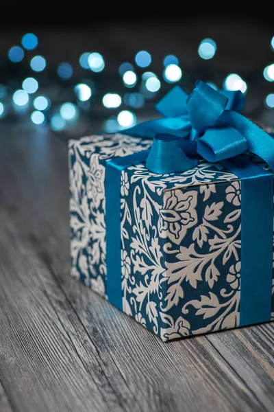 Винтажная рождественская подарочная коробка с голубым бантом на деревянной поверхности — стоковое фото
