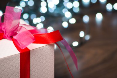 Noel hediye kutu kırmızı yay ve ahşap yüzey ışıkları ile