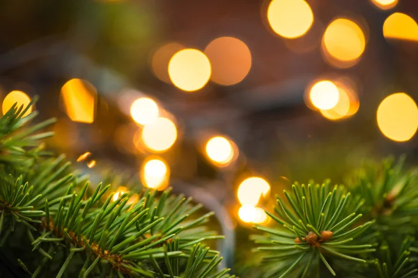 Rama de abeto con luces navideñas sobre la superficie de madera — Foto de Stock