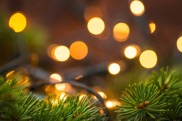 Fir-tree branch with christmas lights over the wooden surface — Stock Photo, Image