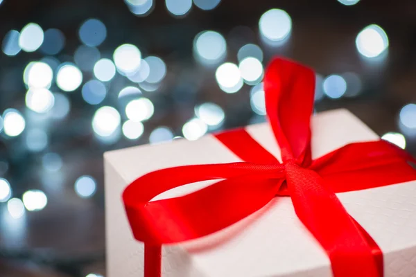 Caja de regalo de Navidad con lazo rojo y luces en la superficie de madera — Foto de Stock