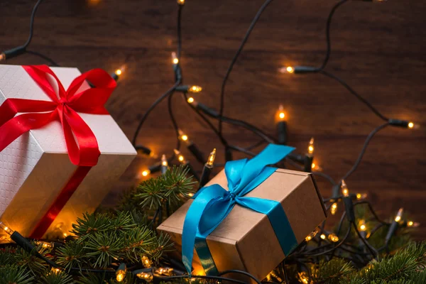 Cajas de regalo de Navidad con arcos rojos y azules y luces en la superficie de madera — Foto de Stock