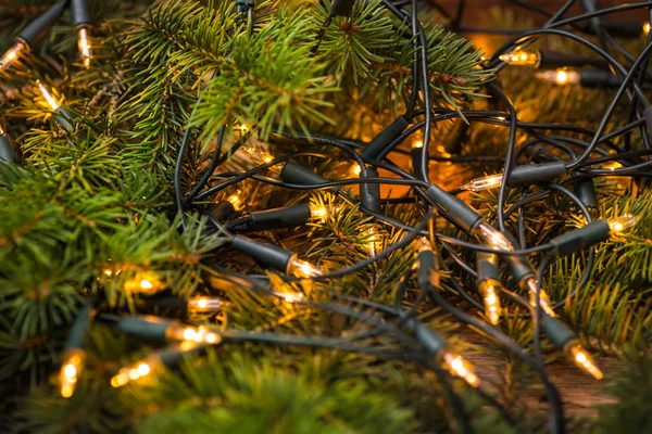 Rama de abeto con luces navideñas sobre la superficie de madera — Foto de Stock