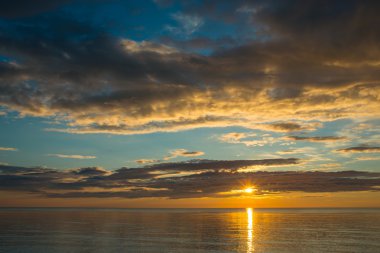 Bulutlu gökyüzü üzerinde sahilde yaz günbatımı