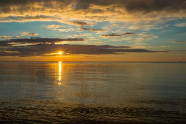 Bulutlu gökyüzü üzerinde sahilde yaz günbatımı