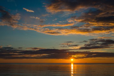 Bulutlu gökyüzü üzerinde sahilde yaz günbatımı