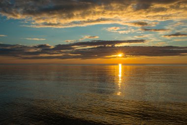 Bulutlu gökyüzü üzerinde sahilde yaz günbatımı