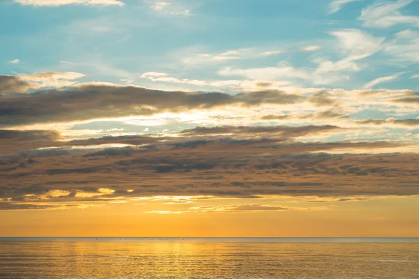 Pôr do sol de verão na praia com nuvens sobre o céu — Fotografia de Stock