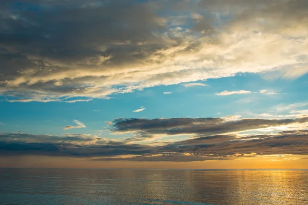 Pôr do sol de verão na praia com nuvens sobre o céu — Fotografia de Stock