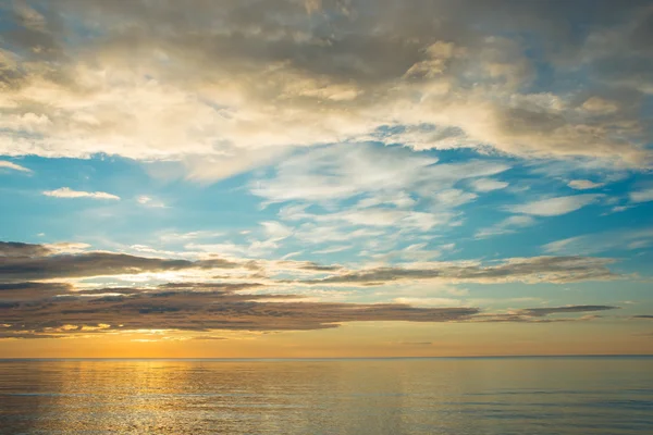 Pôr do sol de verão na praia com nuvens sobre o céu — Fotografia de Stock