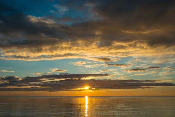 Pôr do sol de verão na praia com nuvens sobre o céu — Fotografia de Stock