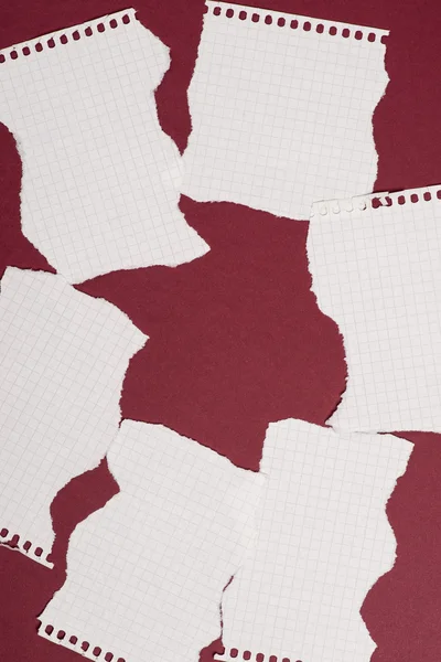 Koyu kırmızı zemin üzerinde yırtık kağıt parçaları — Stok fotoğraf