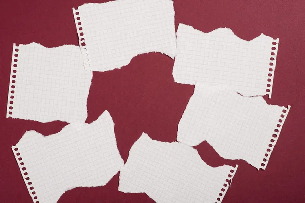 Pieces of torn paper over the dark red background — Stock Photo, Image