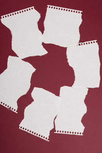 Pieces of torn paper over the dark red background — Stock Photo, Image